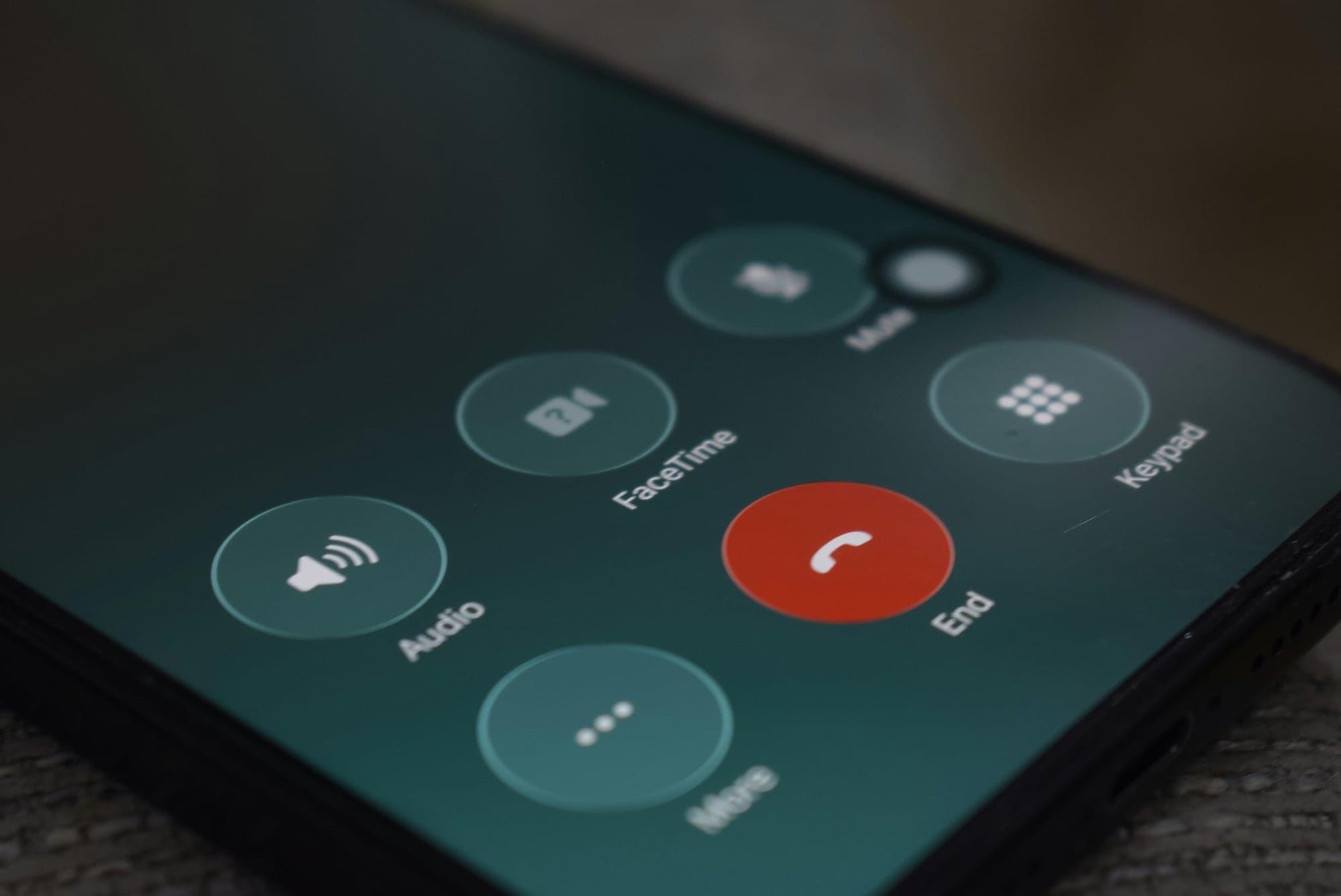 Écran de smartphone en cours d'appel, vu en gros plan : le bouton rouge « End » pour raccrocher entouré des touches Audio, FaceTime, Mute, Keypad et More